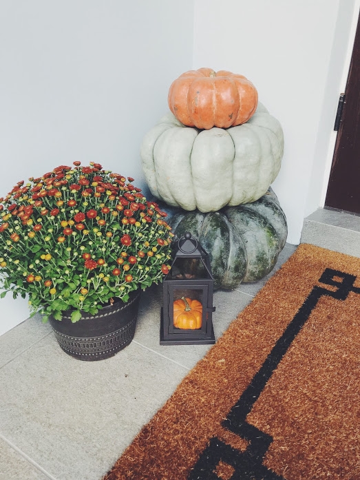 doorstep with multi-colored pumpkins, mums, and decorative lantern