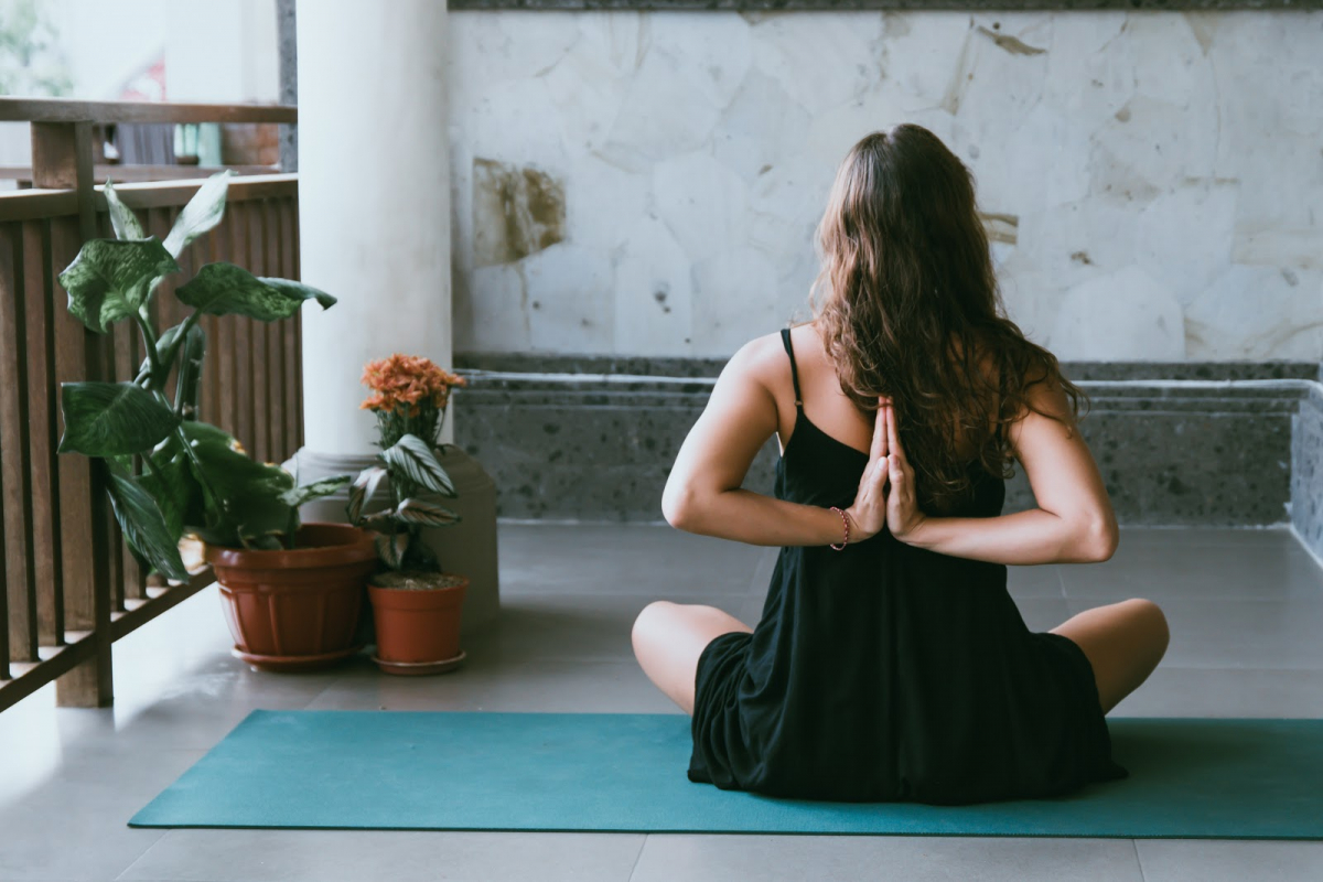 woman doing yoga meditation teal mat black shirt miami fl 