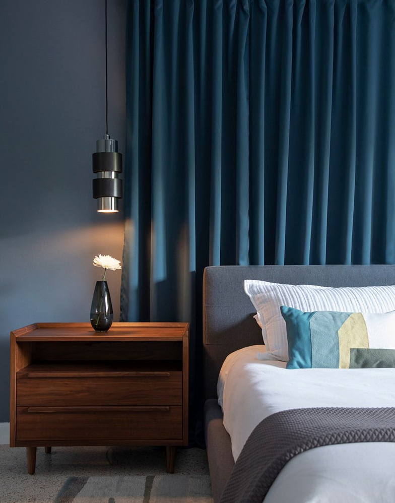 dark moody bedroom hanging pendant light nightstand blue walls drapery miami